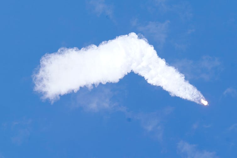 Een raket met een groot spoor van witte wolken in een helderblauwe lucht